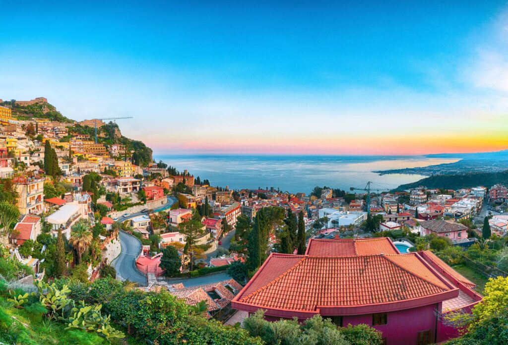 Vista panorâmica de Taormina, na Sicília, com o Mar Jônico ao fundo. Título: Taormina e o Mar Jônico