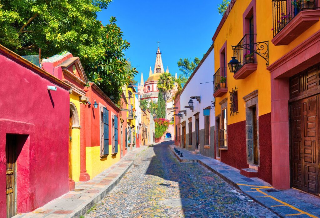 Rua colorida de San Miguel de Allende, no México, com arquitetura colonial e a Paróquia de São Miguel Arcanjo ao fundo.
